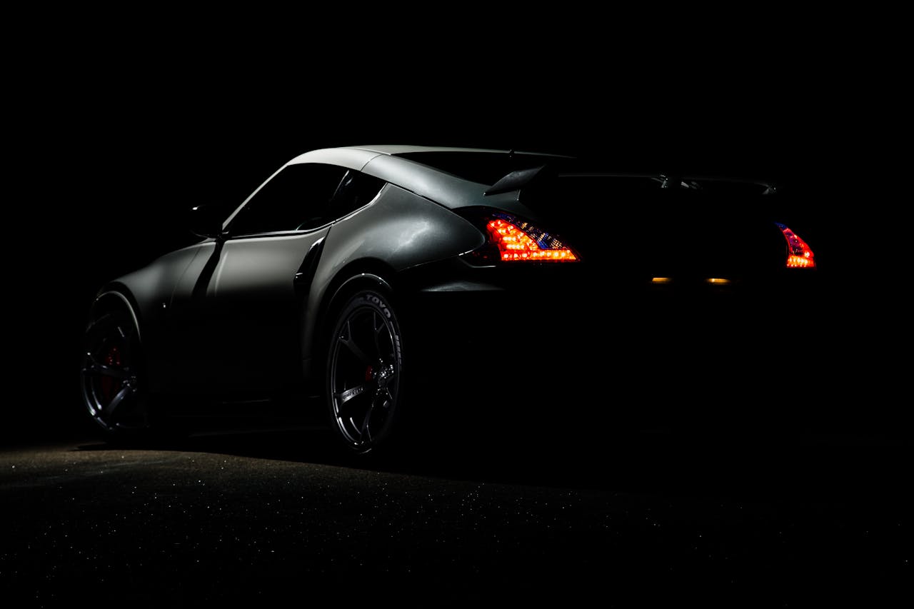 about-02 A dramatic shot of a Nissan 370Z sports car illuminated in darkness with vibrant tail lights.