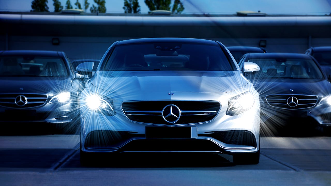 about-03 Front view of a lineup of Mercedes-Benz cars with bright headlights, showcasing luxury and elegance.